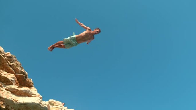 自下而上: 运动游客跳下悬崖，潜入清新的海洋。