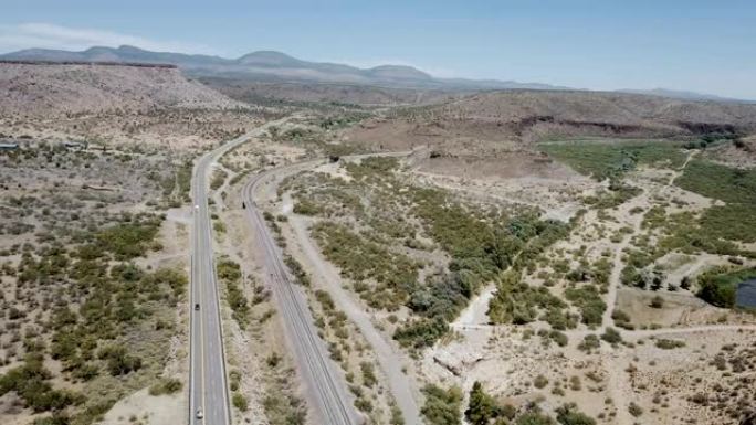 美国亚利桑那州夏季雄伟的沙漠岩石、丘陵、道路和晴朗天空的史诗空中全景。公路旅行概念。