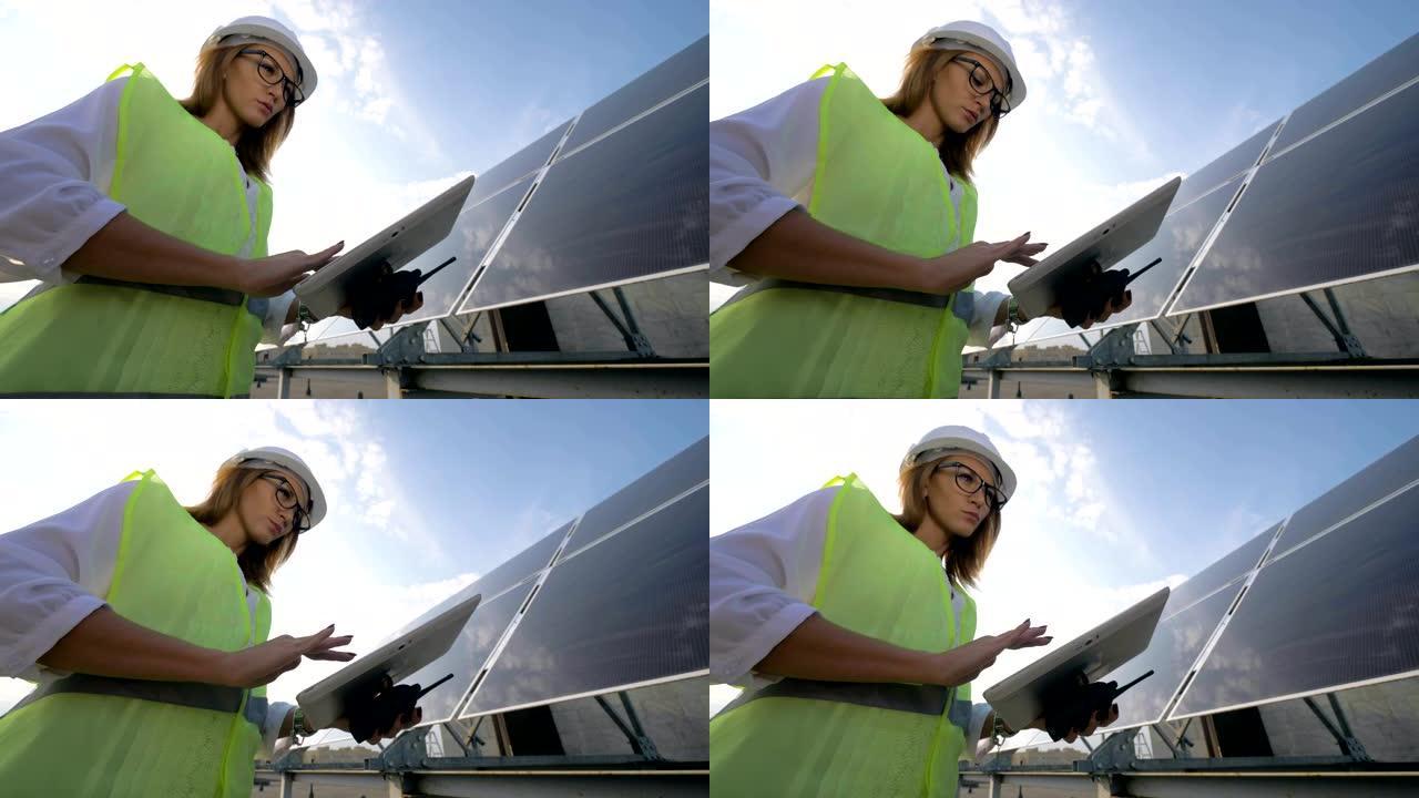 戴眼镜的女太阳能工程师正在用她的计算机站在太阳能电池板旁边工作