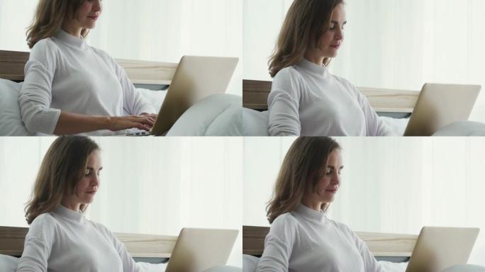 年轻女子坐在床上使用笔记本电脑