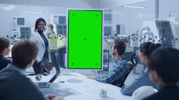 在一次会议上，首席工业工程师向一组专家，经理报告，使用带有绿屏色度键显示的数字白板。专业人员在现代工
