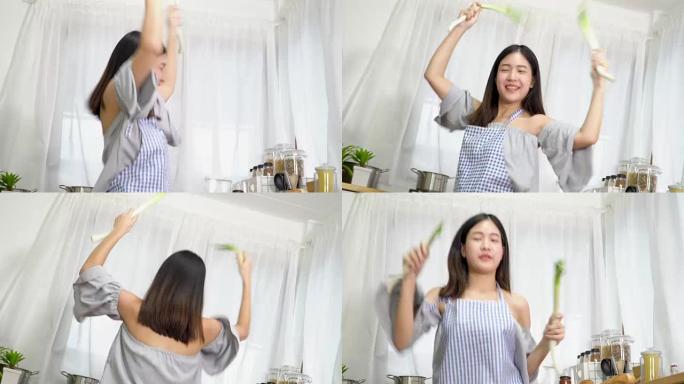 4k; 亚洲女性在厨房里跳舞和拿着蔬菜。