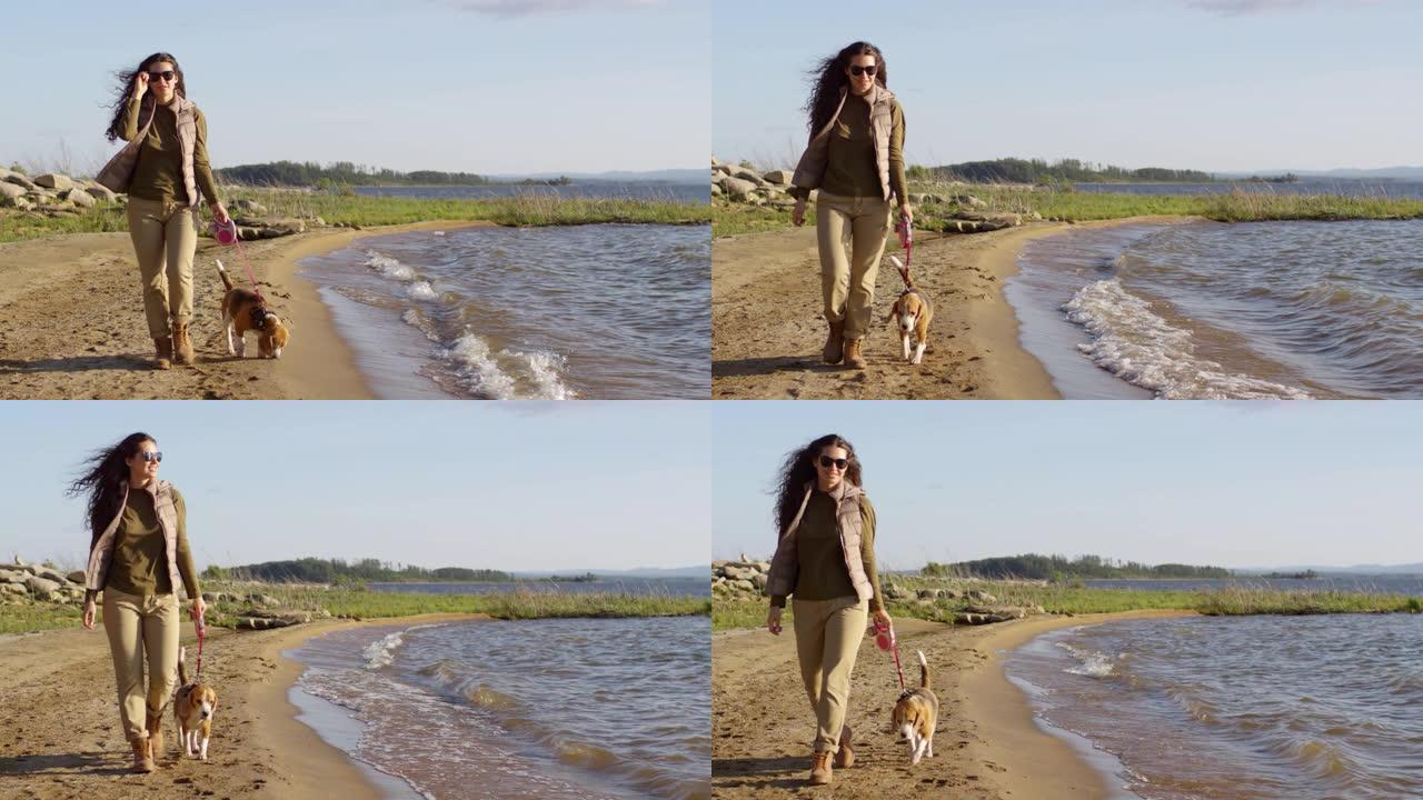 年轻女子喜欢和狗一起沿着湖岸散步
