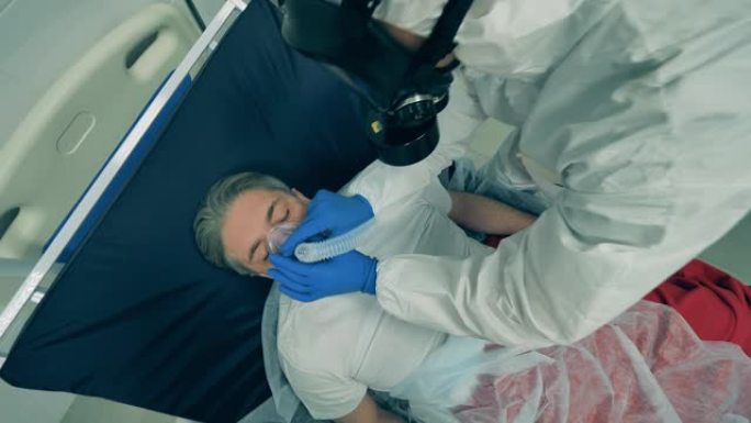医务人员正在将一个人连接到呼吸系统。冠状病毒，新型冠状病毒肺炎医院重症监护室的病人。