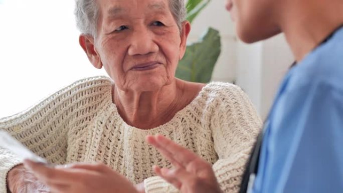 亚洲老年妇女与年轻的黑人女护士交谈医生帮助病人在家接受医疗咨询教育。老年人医疗保健，医疗保健: 护理