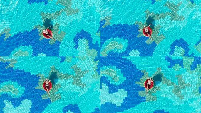 橡胶圈上的年轻女子在蓝色的游泳池里放松。