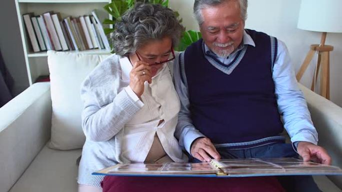 高级夫妇打开相册并记住幸福的时刻，成年父母欣赏家庭相册中的照片，记住青春。退休夫妇花时间看旧相册。