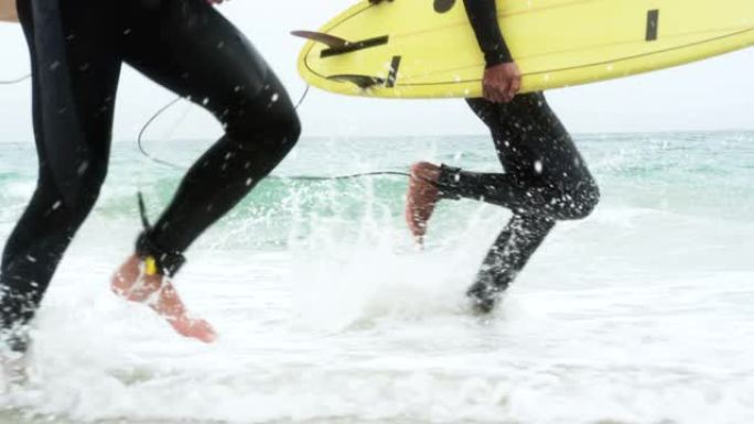 海滩上两个用冲浪板跑步的男性冲浪者的低处4k