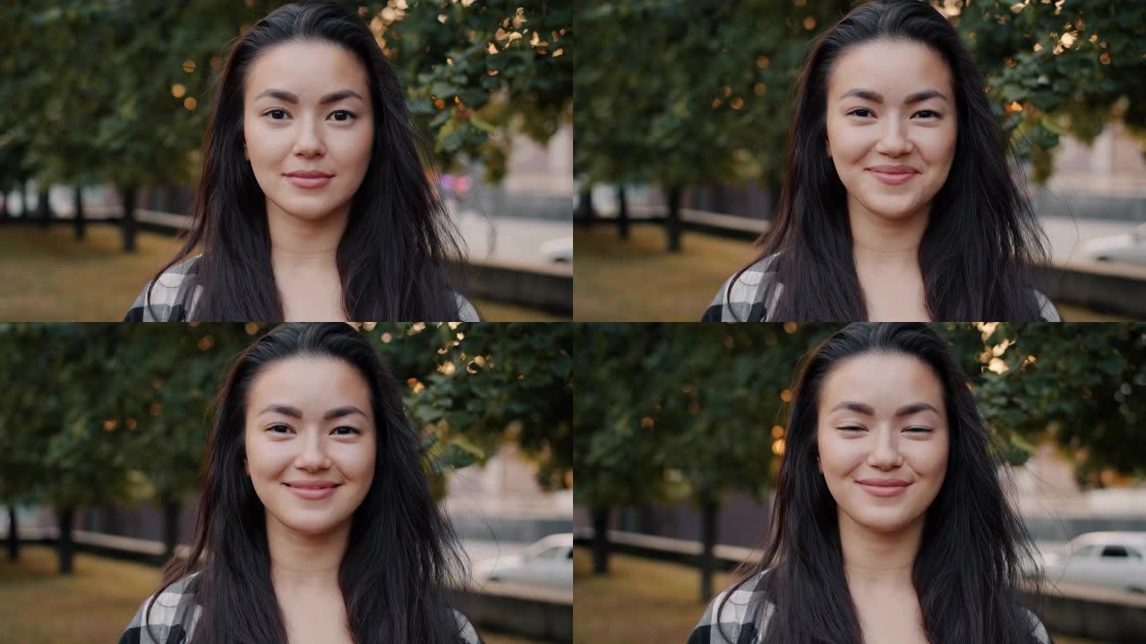 美丽的亚洲学生独自站在城市公园微笑的特写肖像