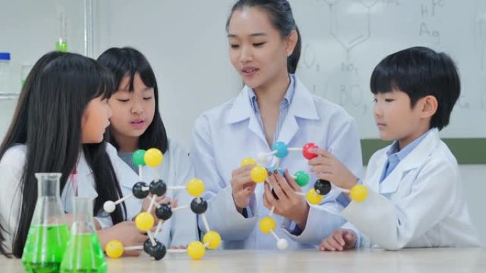 微笑的老师和学生科学家在实验室中观察分子模型。Stem教育。学校的物理实验，孩子们在实验室工作场所构