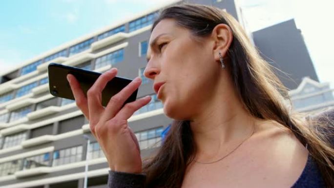 城市4k中女人在手机上说话的低角度视图