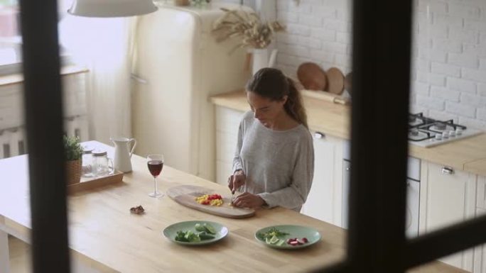 积极的千禧一代女士独自在家准备食物。