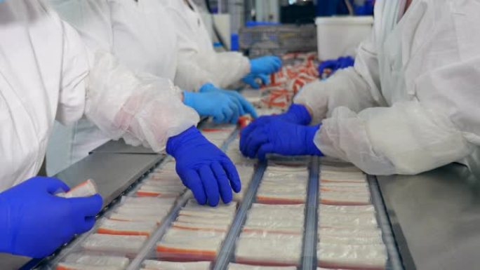 食品厂的工人将产品包装到一条线上的塑料托盘中。