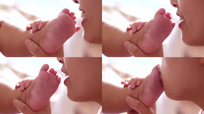 母亲亲吻她的小脚亲婴儿脚