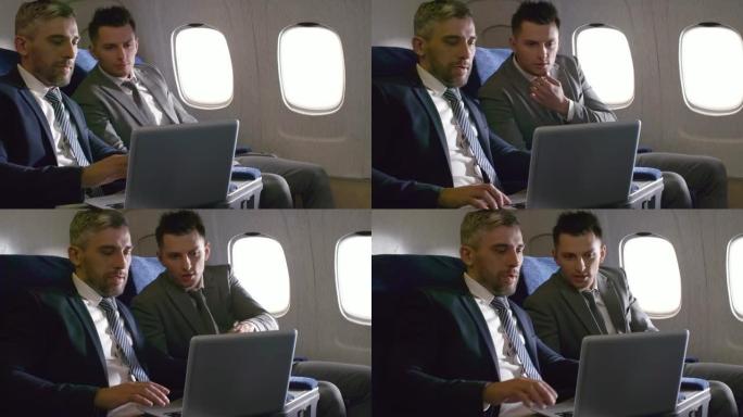 在飞机上使用笔记本电脑工作的商人
