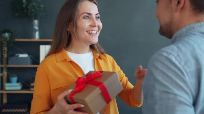 爱的男人祝贺女人送礼盒拥抱在家里表达爱