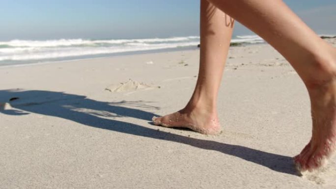 年轻女子在阳光下的海滩上散步4k