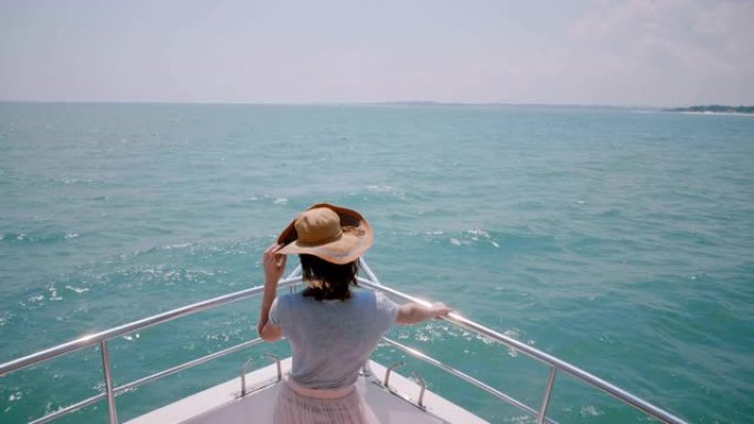 美丽的高角度后视图拍摄快乐成功的旅游女人在游艇船鼻子上享受着惊人的阳光海上航行。