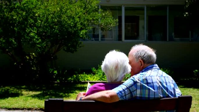 活跃的高加索老年夫妇在养老院4k花园看相册的后视图