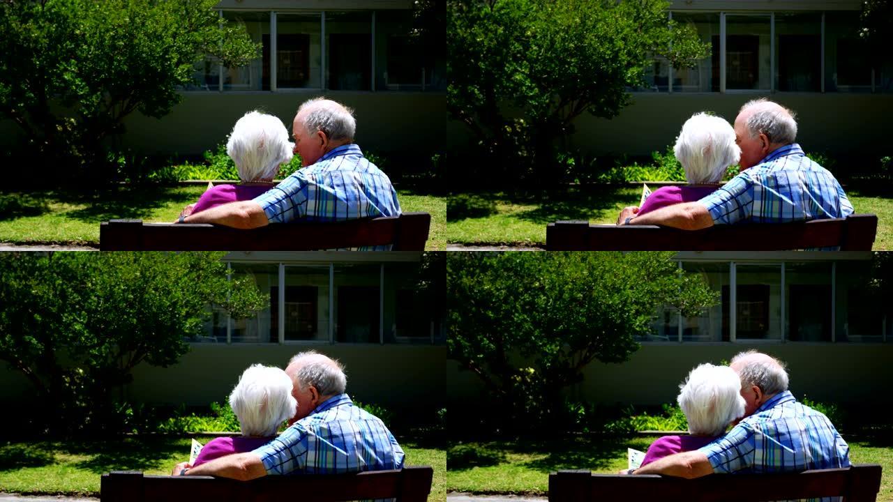 活跃的高加索老年夫妇在养老院4k花园看相册的后视图