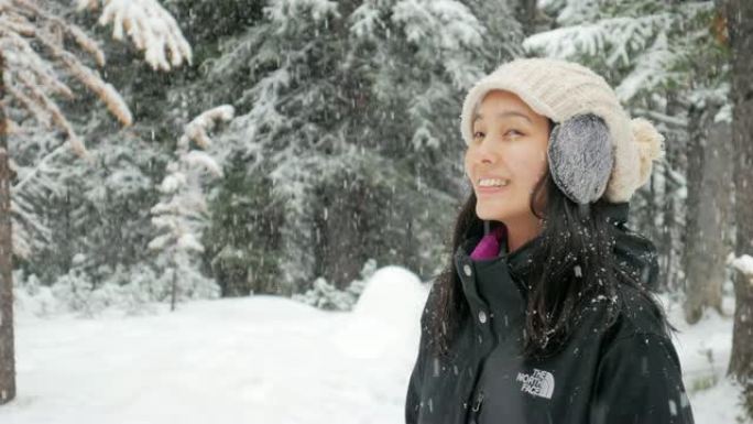 女人在冬天享受着新鲜的雪落在公园里