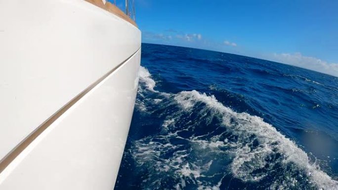 白色游艇的板和慢动作中的蓝色水的侧视图。