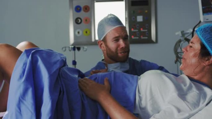高加索女外科医生在手术室中检查孕妇的侧视图