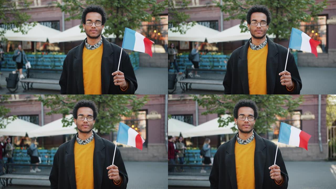 一个非裔美国人站在外面举着法国国旗的慢动作肖像