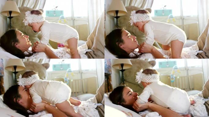 快乐的妈妈和宝宝接吻拥抱，一起躺在床上休息，产妇概念母亲美丽幸福的家庭股票视频镜头慢动作