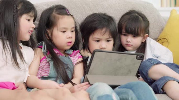 一群在教室里使用平板电脑的孩子，多民族的年轻男孩和女孩在小学里快乐地使用技术学习和玩游戏。孩子们使用