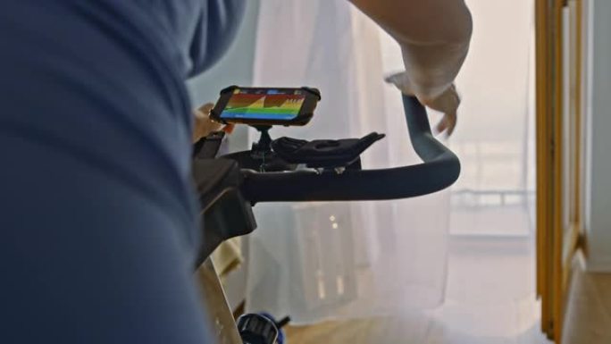 SLO MO女人使用at training移动应用程序在健身车上锻炼