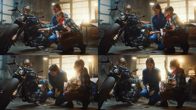两个年轻漂亮的女性正在讨论定制的Bobber摩托车上所做的工作。才华横溢的女孩使用平板电脑。他们精神
