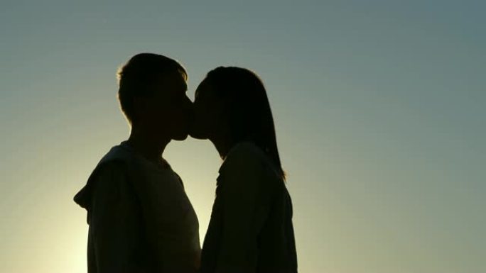 日落4k时浪漫情侣接吻的侧视图