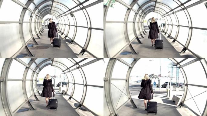 带着手提箱的女商人在阳光明媚的机场隧道中行走