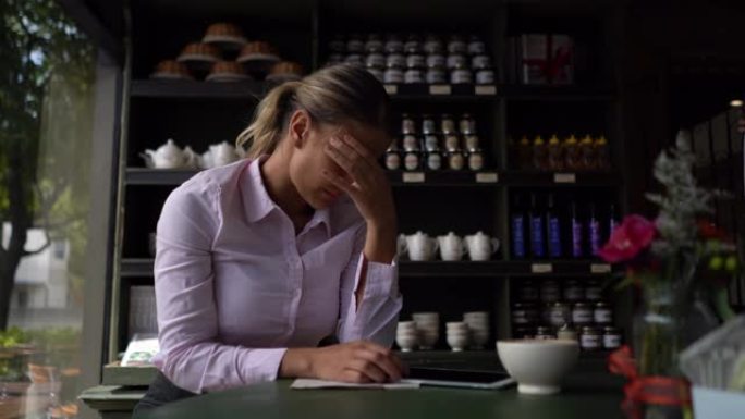 女商人使用她的平板电脑和喝咖啡感到头疼