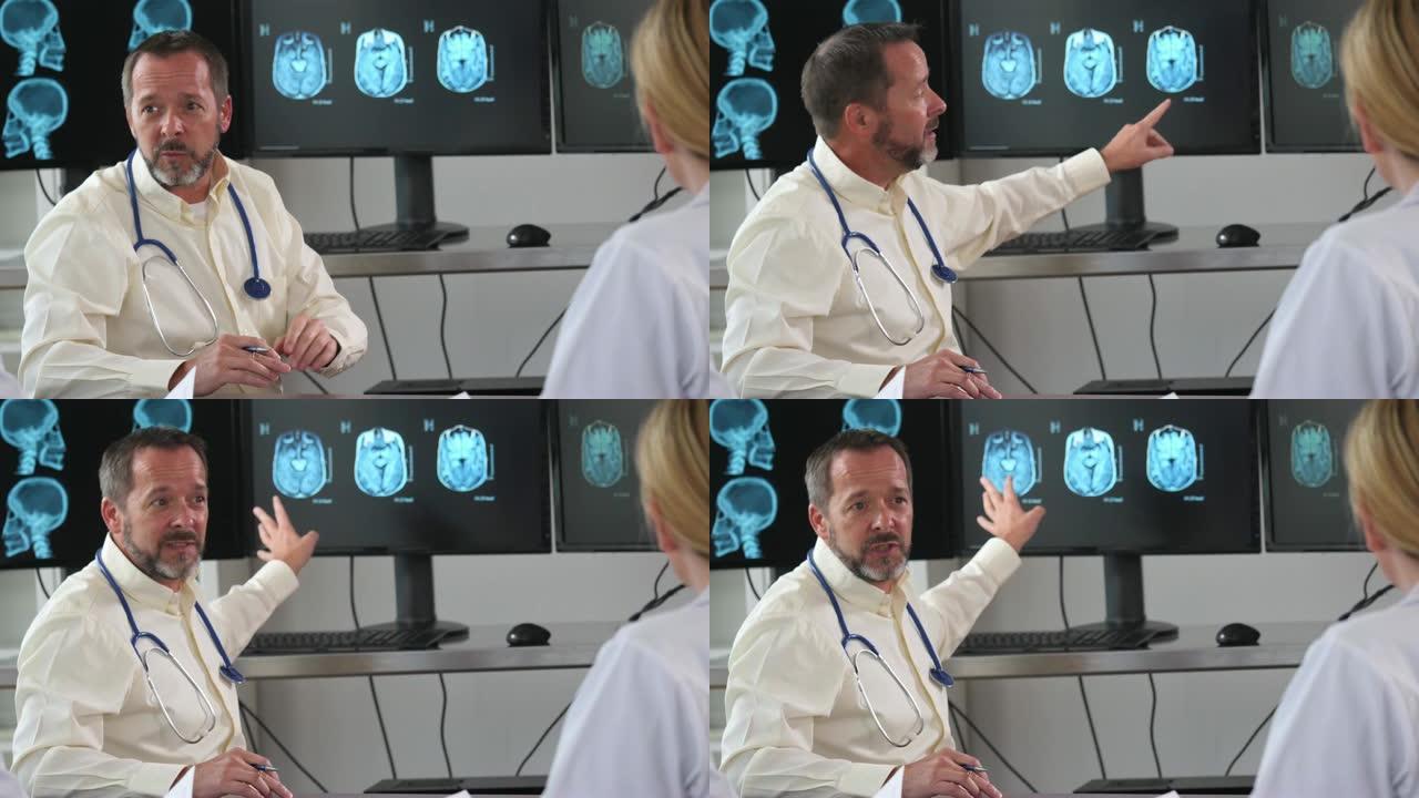 成熟的男性医生在说话时向监视器示意x射线结果