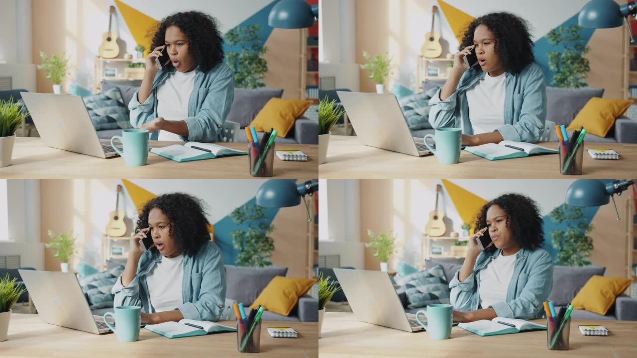 疯狂的非洲裔美国妇女在家中使用笔记本电脑在手机上大喊大叫