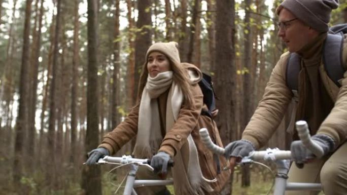 年轻夫妇在秋天的大自然中骑自行车