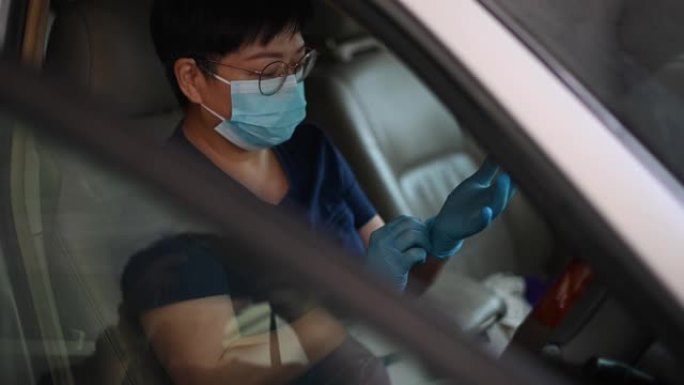 一名亚洲华人女性戴口罩和手套在限制行动期间外出购物前对汽车内部进行消毒和清洁