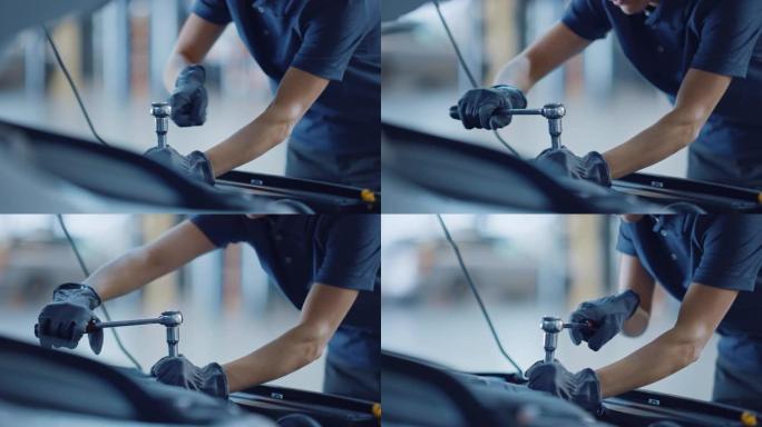 慢动作特写镜头，一名女机械师在汽车服务中工作。赋权女人做通常的汽车保养。她在用棘轮。现代清洁车间。