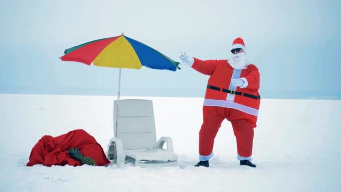 在躺椅和沙滩伞旁边的雪地里跳舞的圣诞老人