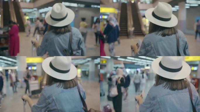 快乐的亚洲女人在国际机场登机口登机时，使用手推车或手推车和许多行李走在航站楼大厅。女人在机场概念中快