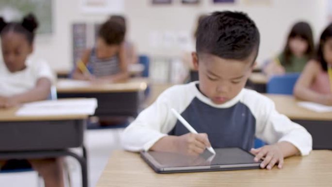 在教室里用数字平板电脑工作的民族小学生