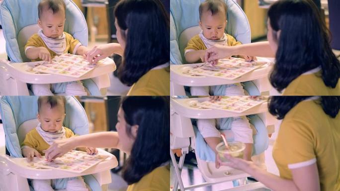 新妈妈和开朗的男婴微笑着吃饭