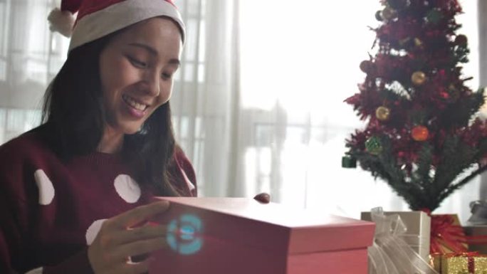 年轻的亚洲妇女在圣诞节庆祝活动中打开了一个发光的礼品盒
