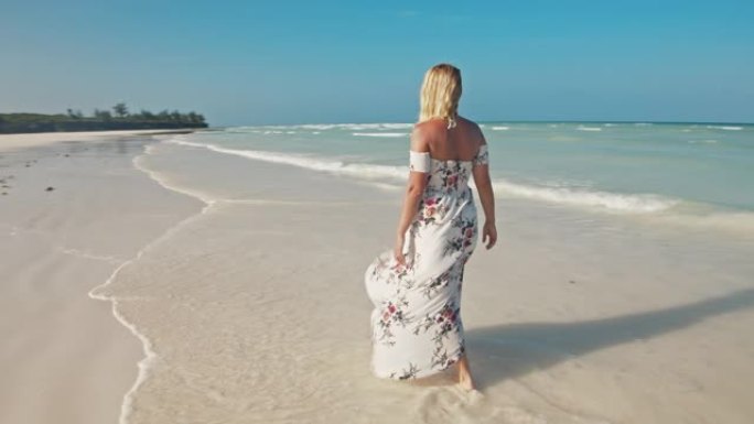 穿着长裙的SLO MO女人在沙滩上行走