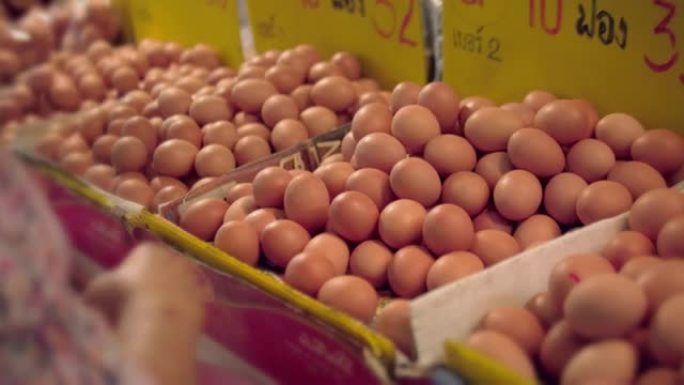 亚洲高级妇女在农贸市场购买鸡蛋