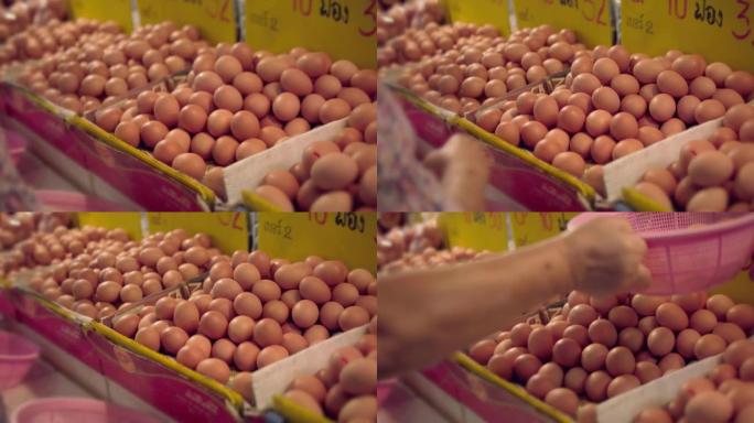 亚洲高级妇女在农贸市场购买鸡蛋