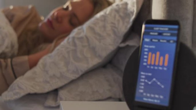 床上睡觉的女人床边用手机运行睡眠数据App