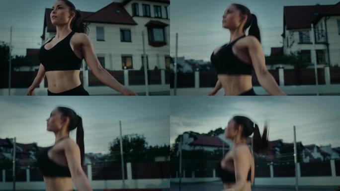 一个美丽丰满的健身女孩跳绳的特写镜头。她正在一个有围栏的室外篮球场里锻炼身体。居民区下雨后的晚间录像